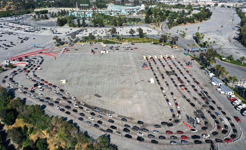 People in cars line up to be tested for Covid-19 in a parking lot at Dodger Stadium, in Los Angeles, California. AFP