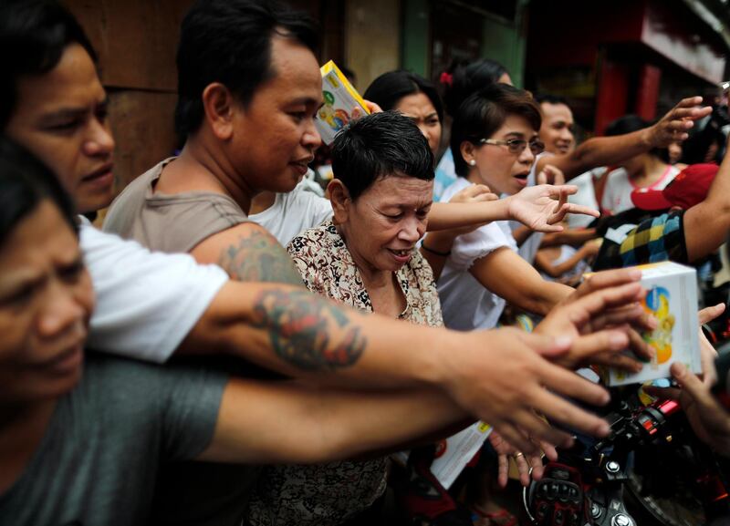 Filipino villagers receive bags of goods from motorcycle riders.  EPA