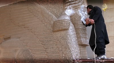 A screengrab from a video reportedly released by ISIS shows a militant destroying the statue of Lamassu, an Assyrian deity, with a jackhammer in Nineveh, Iraq. AFP