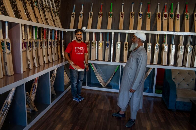 Azhar Bhat bounces a ball on a bat to demonstrate its quality to a customer at his showroom in Sangam, south of Srinagar.
