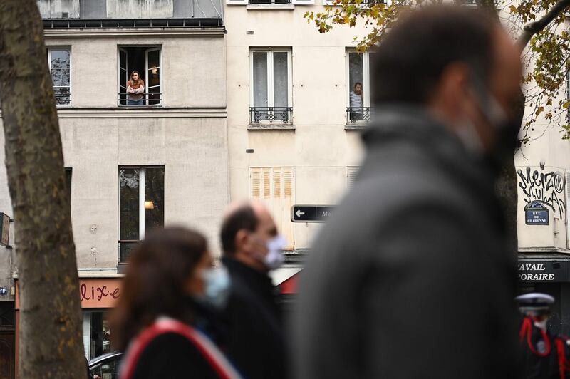 A woman looks out from her window as tributes are paid outside La Belle Equipe bar in Paris. AFP