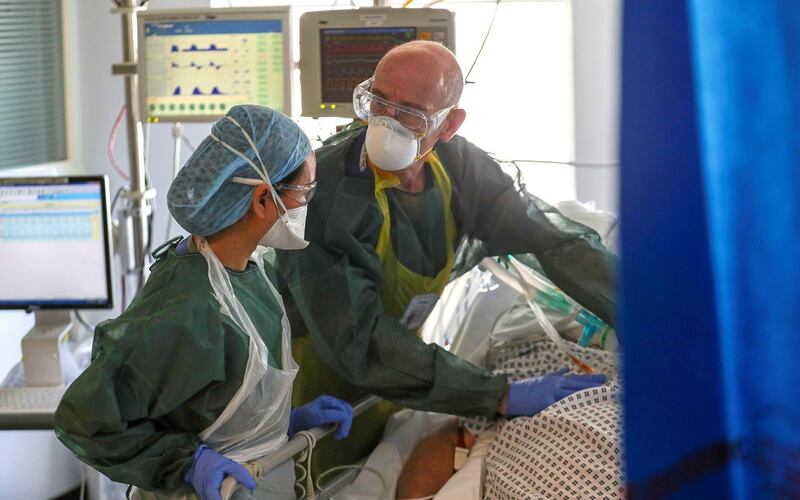 Medical staff wearing full PPE (personal protective equipment), including a face mask, long apron, and gloves as a precautionary measure against COVID-19, treat a patient with COVID-19, on an Intensive Care Unit (ICU) ward at Frimley Park Hospital in Frimley, southwest England on May 22, 2020.
 Britain's number of deaths "involving" the coronavirus has risen to 46,000, substantially higher than the 36,914 fatalities officially reported so far, according to a statistical update released Tuesday. / AFP / POOL / Steve Parsons
