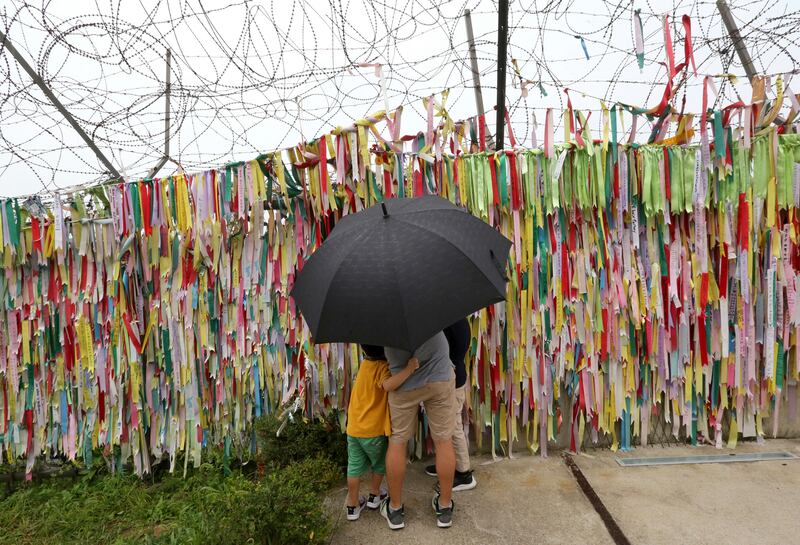 A family hangs a ribbon wishing for reunification of the two Koreas at the Imjingak Pavilion, in Paju, South Korea. Ahn Young-joon / AP Photo