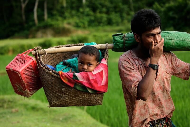 A Rohingya man carries his baby in a basket  as he arrives in Tuangiri, Teknaf, Bangladesh. Abir Abdullah / EPA