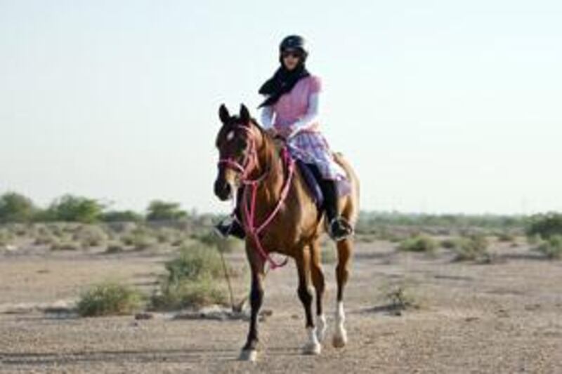 Hanan al Muhairi, 24, of Ras al Khaimah, takes a ride in the desert on a horse from the police stables.