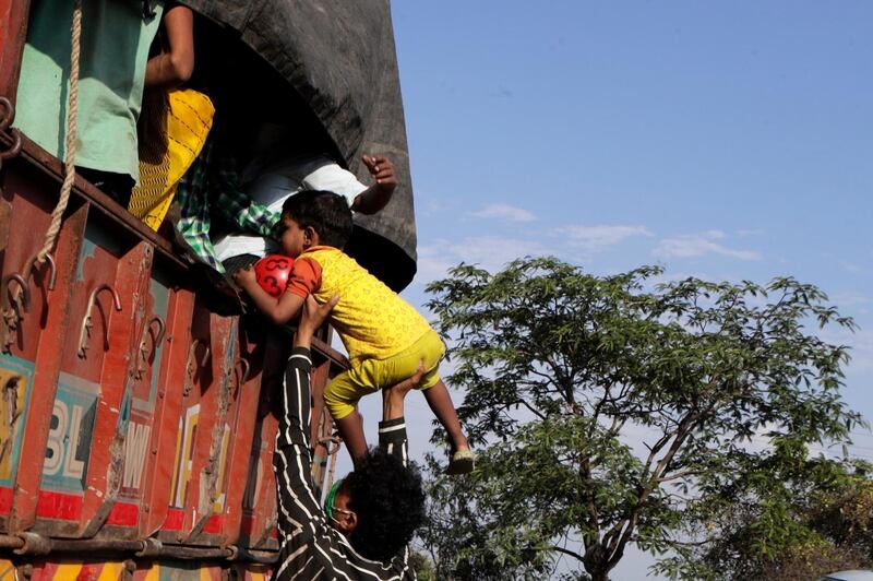 A migrant workers' family desperate to reach their home in neighbouring Madhya Pradesh state hitchhike behind a lorry  in India's commercial capital Mumbai that will take them to the outskirts of the city. India’s train network, closed in late March, will gradually restart operations on Tuesday as the country eases its lockdown amid a steep rise in the coronavirus infections. AP Photo