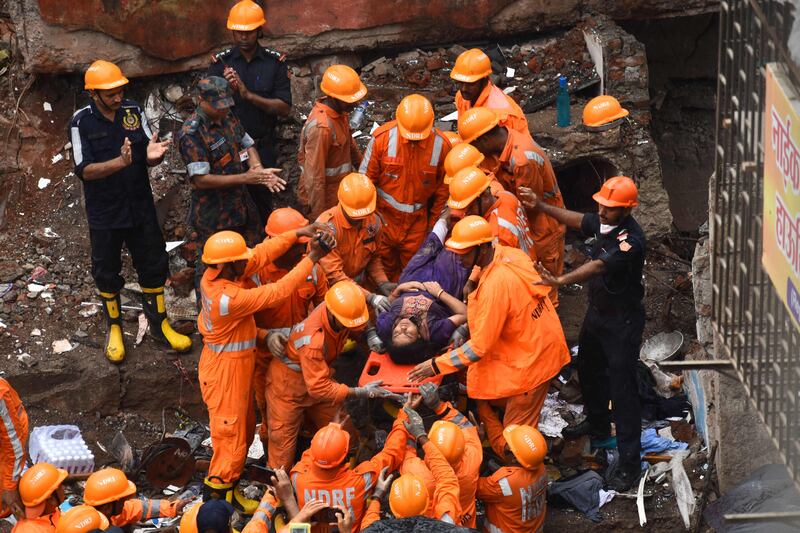 Rescue workers cheer as a survivor is brought out alive on a stretcher from the debris of a collapsed building in Mumbai on June 28. AFP