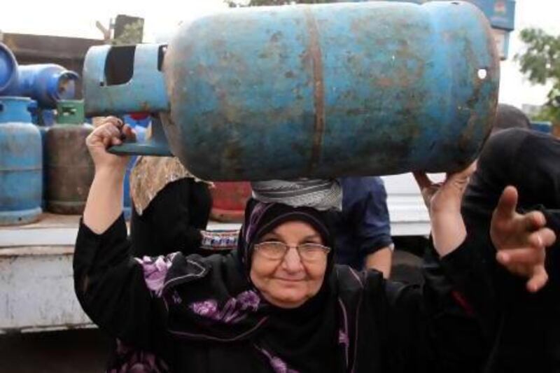 A woman carries a gas cylinder distributed by the army in Cairo. Even before the uprising in the country, the government often had problems delivering subsidised consumer goods to the poor.