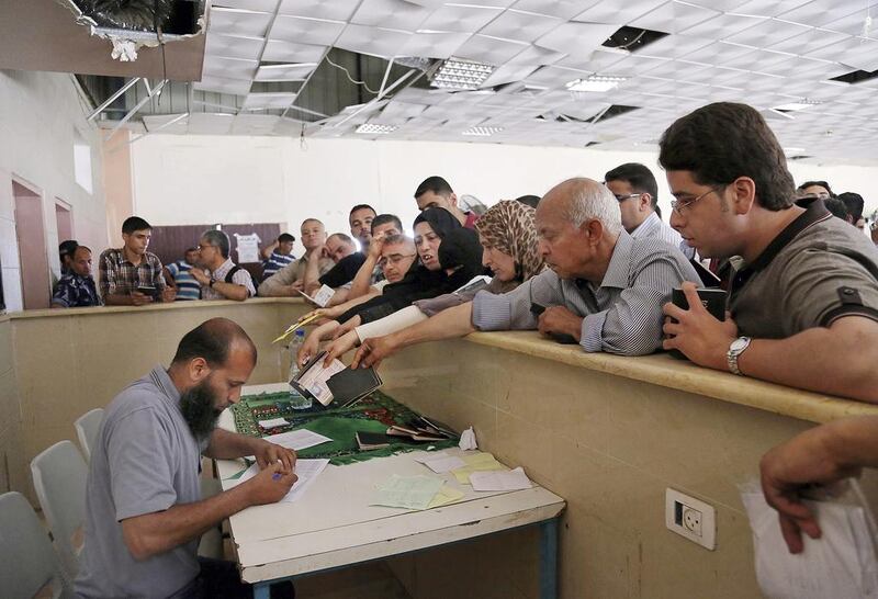 Palestinians thrust their passports and documents at a border officer as they wait to cross to the Egyptian side of the Rafah border crossing, in the southern Gaza Strip, on June 13, 2015. Adel Hana/AP Photo