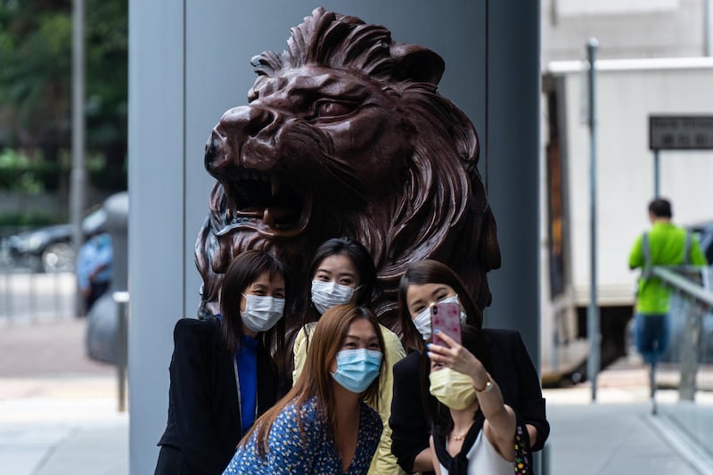 People take a selfie photograph with a statue of a lion in front of the HSBC Holdings Plc headquarters building in Hong Kong, China. Bloomberg