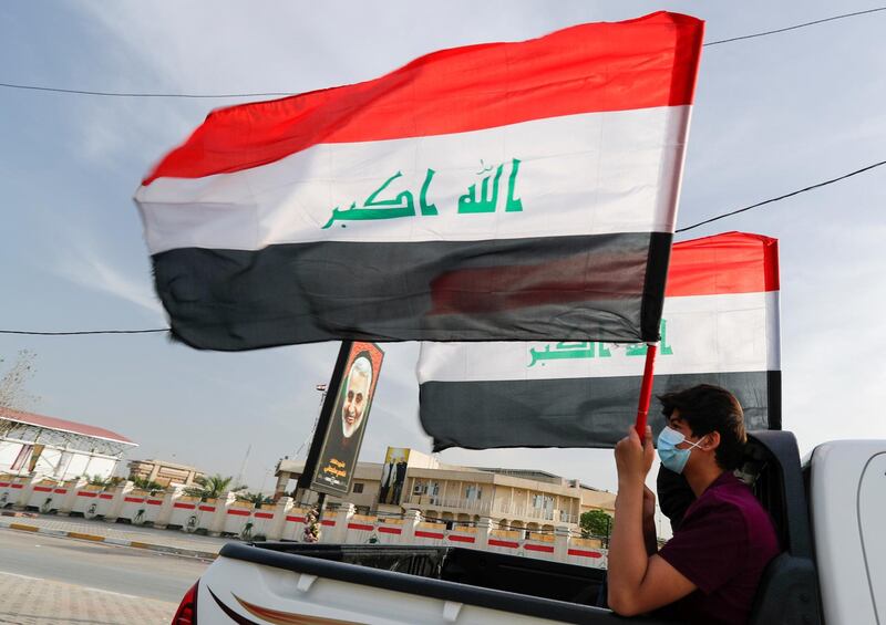 A member of Kataib Hezbollah paramilitary group holds an Iraqi flag and travels in a vehicle as he takes part in a parade ahead of the annual Quds Day, or Jerusalem Day, during the Muslim holy month of Ramadan, in Baghdad, Iraq May 6, 2021. REUTERS/Thaier Al-Sudani