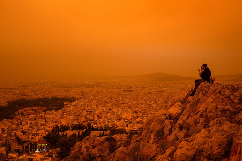 A couple sit on Tourkovounia hill, as southerly winds carry waves of Saharan dust, in Athens. AFP