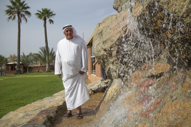 Ali Al Mahrazi proudly stands next to one of the waterfalls he built on his property, which he named the Masafi Water Falls and Cave, left. Mona Al Marzooqi / The National 