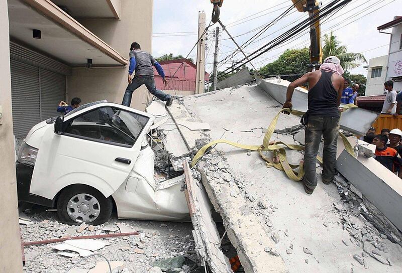 Workers use a crane to lift up concrete block that fell on a car after buildings collapsed during an earthquake in Cebu city, central Philippines October 15, 2013.  Reuters/Stringer 