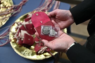 The red Maundy purses each contain a £5 coin which features the image of a Tudor Dragon, and a 50p coin commemorating the RNLI. AFP