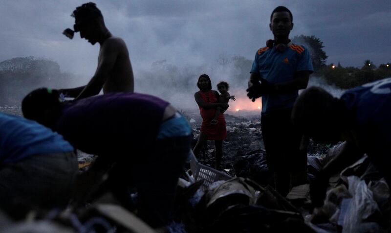 A mother holds her child as Venezuelans looking for recyclables at a landfill  in Pacaraima, Brazil. Reuters