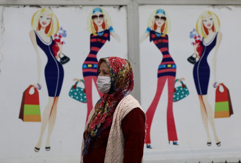 A Turkish woman, wearing a face mask for protection against the coronavirus, walks past a closed shop, in Ankara, Turkey. AP
