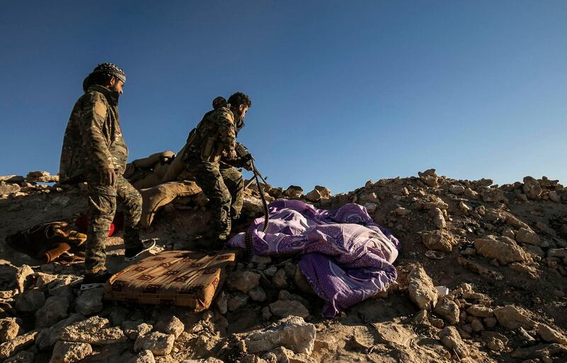 Fighters with the Syrian Democratic Forces keep position at a hilltop overlooking ISIS's last remaining redoubt in Baghouz, eastern Syria.  AFP