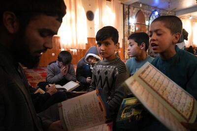 Sanam sits among Afghan boys as they read the Quran during a class at a mosque, in Kabul. AP