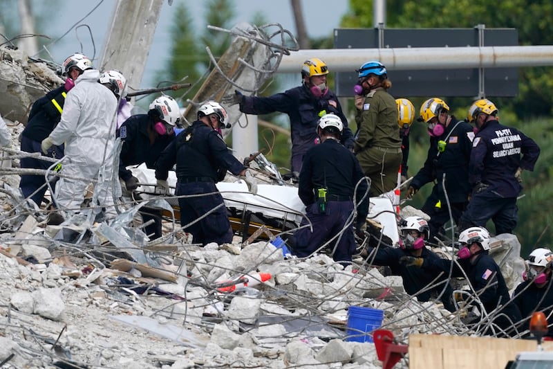 Rescue workers move a stretcher containing recovered remains at the site of the collapsed Champlain Towers South condo building in Surfside, Florida. AP