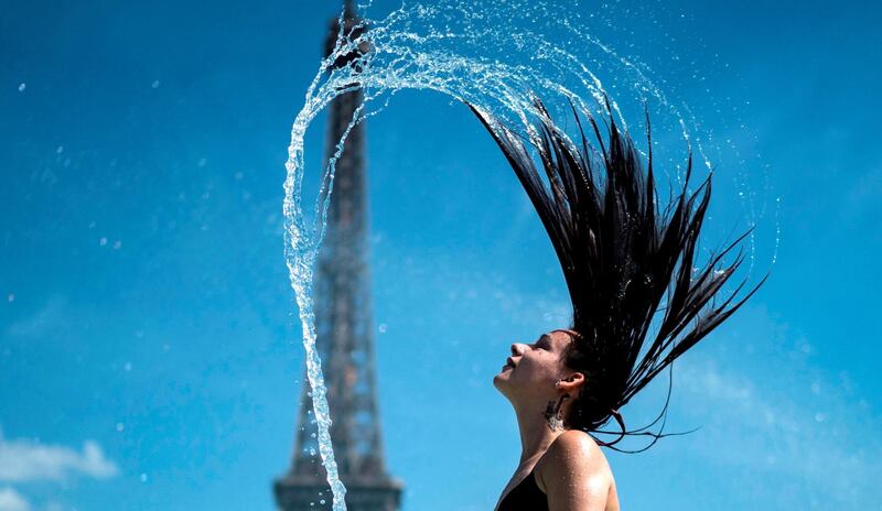 A woman plays the water as she cool herself down in the fountain of the Trocadero esplanade in Paris on June 25, 2019 with the Eiffel Tower on the background. Forecasters say Europeans will feel sizzling heat this week with temperatures soaring as high as 40 degrees Celsius (104 degrees Fahrenheit) in an "unprecedented" June heatwave hitting much of Western Europe. / AFP / Kenzo TRIBOUILLARD
