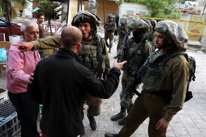 epa08428445 Israeli soldiers on patrol stop Palestinians in the Old City of the West Bank town of Hebron, 17 May 2020.  EPA/ABED AL HASHLAMOUN