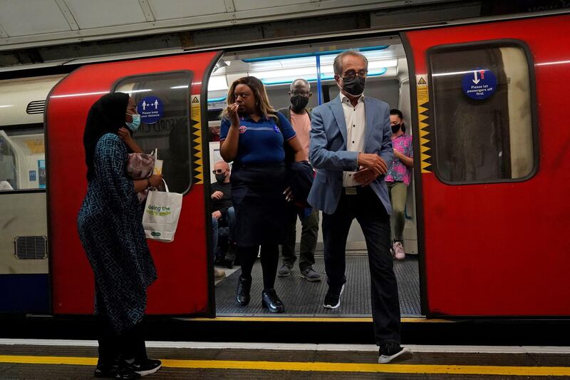Commuters wearing face coverings travel on an underground train in central London. AFP