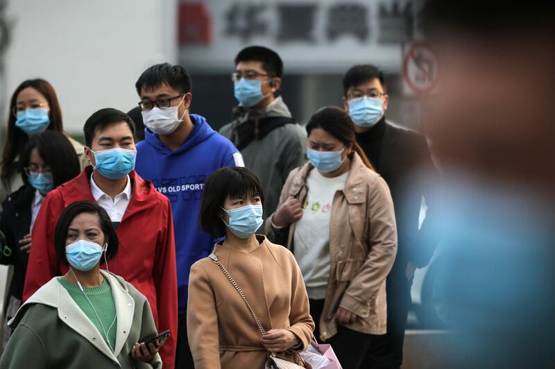 People wearing face masks to help curb the spread of the coronavirus walk out from a subway station entrance gate during the morning rush hour in Beijing.  AP Photo