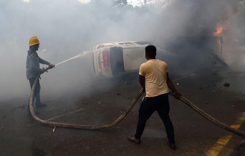 Indian firemen put out a burning vehicle belonging to a member of the media. Altaf Qadri / AP Photo
