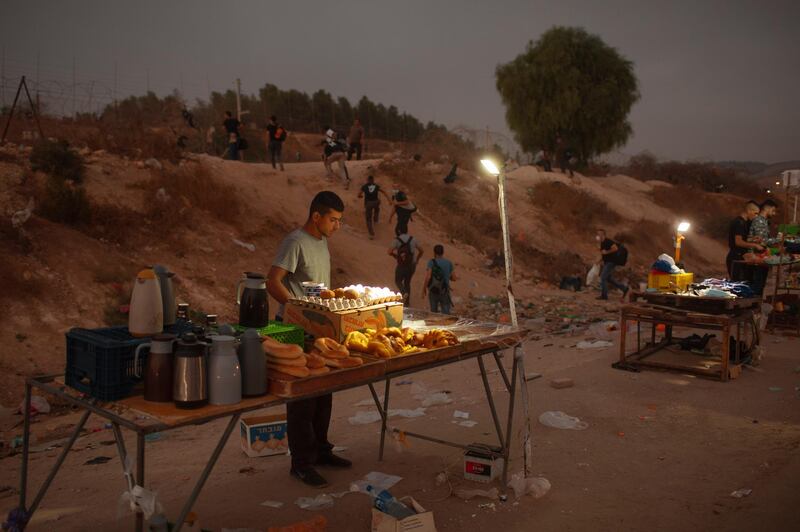 A Palestinian vendor sells food as Palestinian labourers cross illegally into Israel from the West Bank through an opening in a fence, south of the West Bank town of Hebron. AP Photo