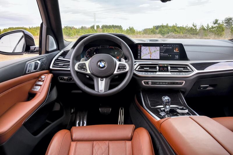 The M logo appears on the steering wheel and gear lever and the upholstery is largely contrast stitched leather. Much of the hard surface area is high-gloss wood and metal. Courtesy BMW