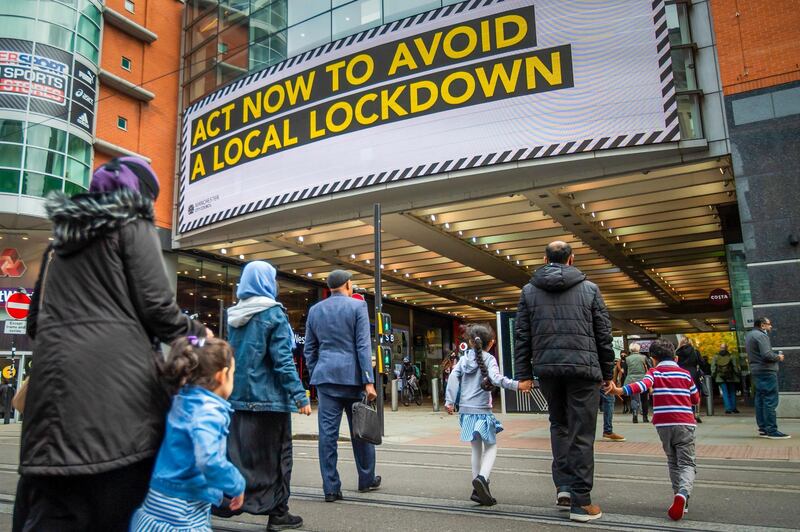 Pedestrians pass a large advertisement on the Arndale Centre shopping mall reading "Act now to avoid a local lockdown" in Manchester. Bloomberg