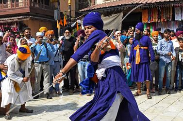 A Nihang or Sikh warrior performs 'Gatka', an ancient form of Sikh martial arts, during a religious procession on the eve of the birth anniversary of the fourth Sikh Guru Ram Das outside the Golden Temple in Amritsar on October 21, 2021.  (Photo by Narinder NANU  /  AFP)