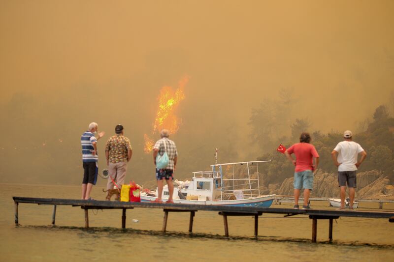 Tourists wait to be rescued from the smoke-engulfed Mazi area as bush fires edge towards the shore, in Bodrum, Turkey.  More than 100 wildfires have been brought under control in Turkey, officials say.