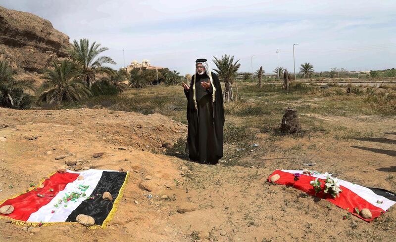 FILE - In this April 3, 2015 file photo, an Iraqi man prays for his slain relative, at the site of a mass grave, believed to contain the bodies of Iraqi soldiers killed by Islamic State group militants when they overran Camp Speicher military base, in Tikrit, Iraq. U.N. investigators have collected millions of call data records implicating Islamic State militants in atrocities committed in northern Iraq, but delays in passing a law to govern war crimes probes is hindering the pursuit of justice, according to the head of the investigation. (AP Photo/Khalid Mohammed, File)