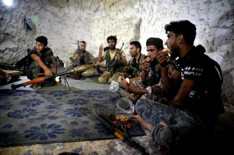 FILE - In this Sunday, Sept. 9, 2018 file photo, fighters with the Free Syrian army eat in a cave where they live, in the outskirts of the northern town of Jisr al-Shughur, Syria, west of the city of Idlib. As the decisive battle for Idlib looms, a motley crew of tens of thousands of Syrian opposition fighters, including some of the world's most radical, are digging their heels_ looking for ways to salvage what is possible of an armed rebellion that at one point in the seven-year conflict controlled more than half of the country. (Ugur Can/DHA via AP, File)