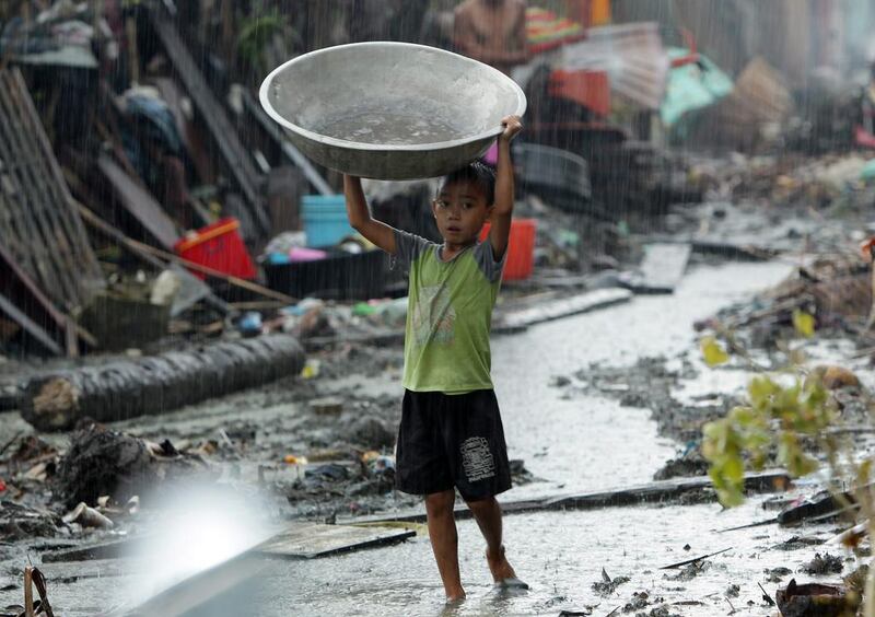 A Filipino typhoon victim carrying a basin walks among debris in the typhoon devastated town of Basey, Samar island province, Philippines.  Francis Malasig/EPA