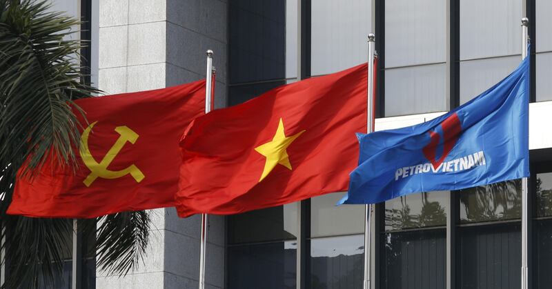 FILE PHOTO: Flag of PetroVietnam (R) flutters next to Vietnamese national flag (C) and Communist Party flag in front of the headquarters of PetroVietnam in Hanoi January 11, 2016.    REUTERS/Kham/File Photo