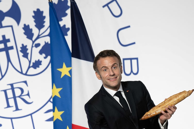 Mr Macron is presented with a baguette during the reception. AFP