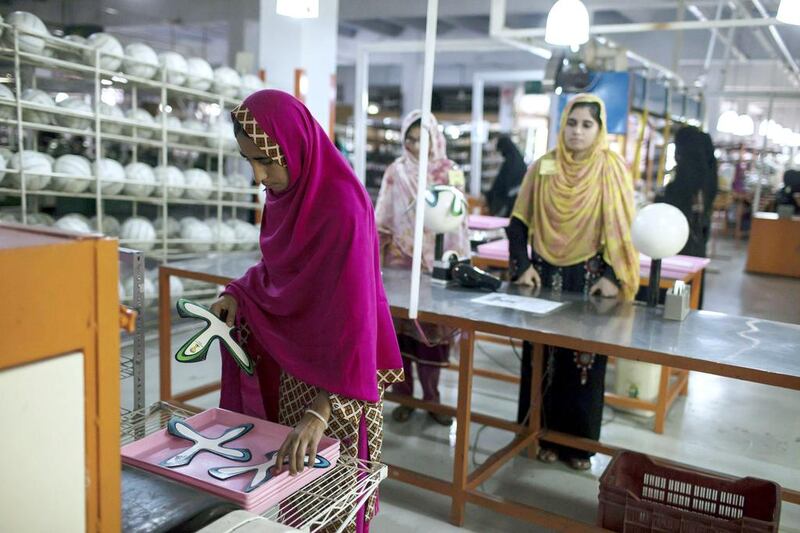 An employee collects ball panels from a machine that applies adhesive at the edges inside the football factory that produces official match balls for 2014 World Cup in Brazil, in Sialkot, Punjab province. Sara Farid / Reuters