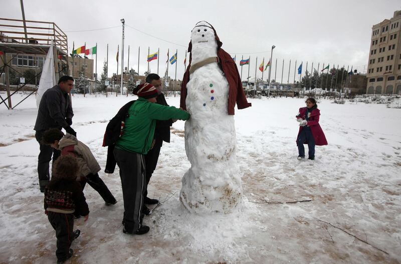 Palestinians build a snowman in the West Bank city of Ramallah on January 10, 2013. Abnormal storms which have blasted the Middle East with rain, snow and hail have claimed at least 11 lives in a region accustomed to temperate climates. AFP PHOTO/ABBAS MOMANI

