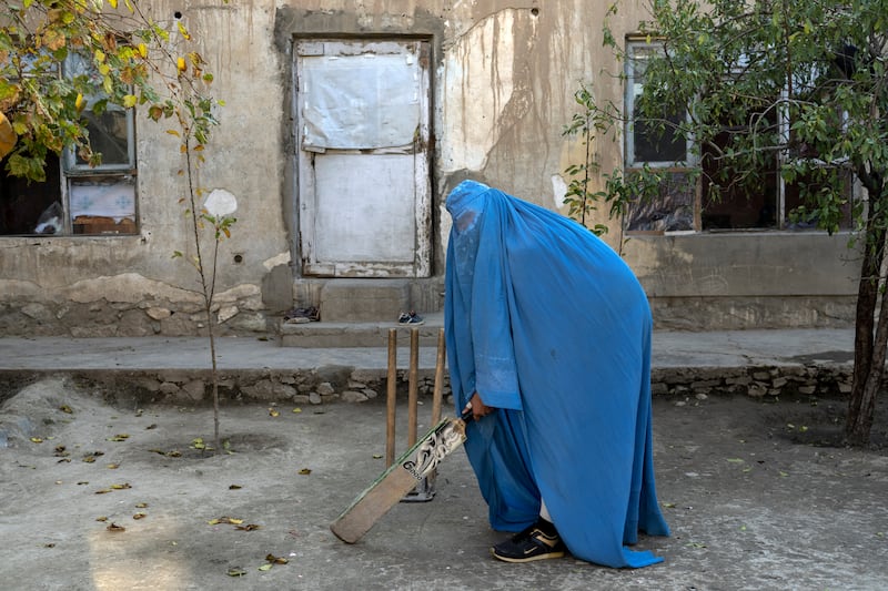 An Afghan woman with her cricket bat in Kabul. The Taliban have issued bans on girls' education and barred women from many types of work.