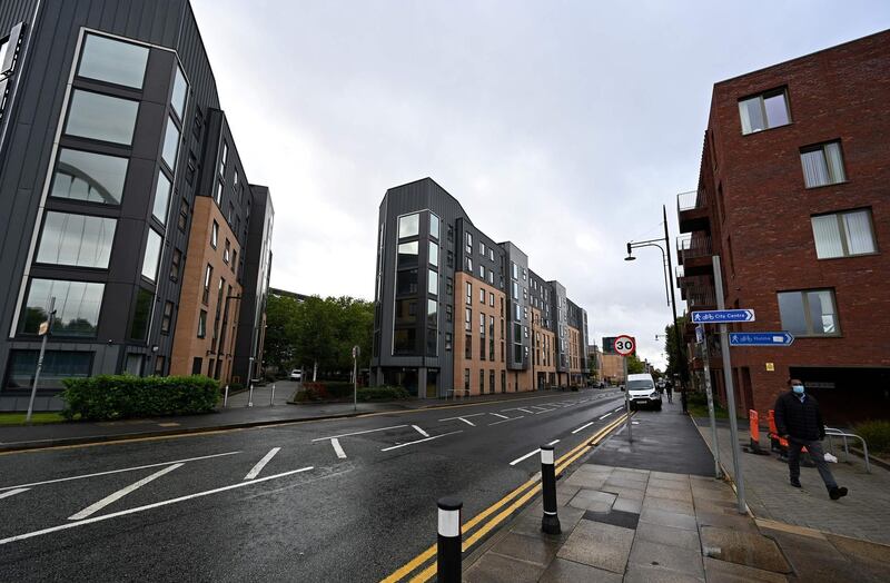 A man wearing a face mask walks along an empty street near the University in Manchester. AFP