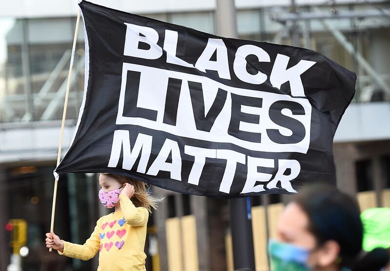 epa09105723 A young girl holds a flag reading 'Black Lives Matter' (BLM) as protesters march through downtown Minneapolis on the first day of opening statements for the murder trial of former Minneapolis police officer Derek Chauvin who was charged in the death of George Floyd, in Minneapolis, Minnesota, USA, 29 March 2021.  EPA/CRAIG LASSIG