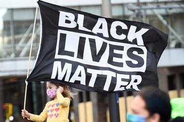 A young girl holds a flag reading 'Black Lives Matter' as protesters march through downtown Minneapolis on the first day of opening statements for the murder trial of former Minneapolis police officer Derek Chauvin who was charged in the death of George Floyd. EPA