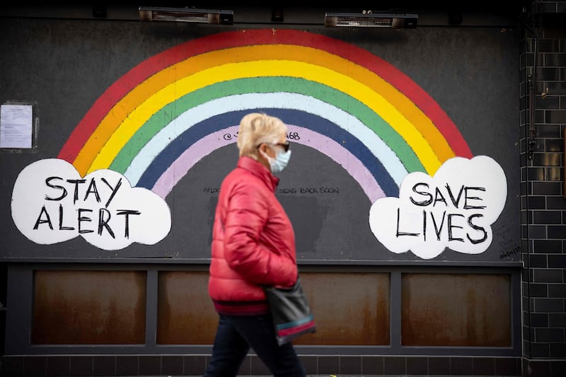 A pedestrian wearing a face mask walks past Cstreet art, advising to "Stay Alert" and "Save Lives" in central London. AFP