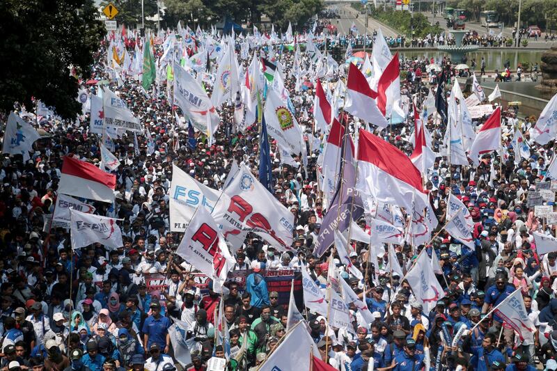 Indonesians wave flags as they march along a road towards the Presidential Palace during a May Day rally in Jakarta, Indonesia. Bagus Indahono / EPA