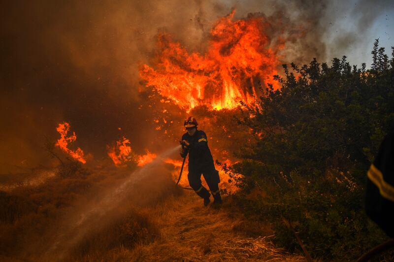 A firefighter tackles a blaze in the village of Markati, near Athens. More wildfires broke out on Monday in Greece, parts of which have been burning for more than two weeks, fanned by strong winds.