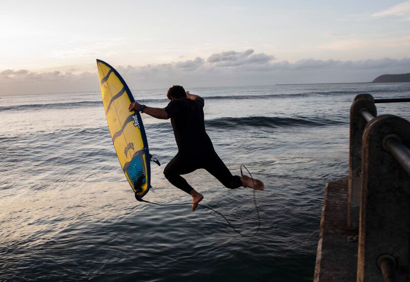 A surfer jumps into the sea off a pier on the beachfront in Durban, South Africa. EPA