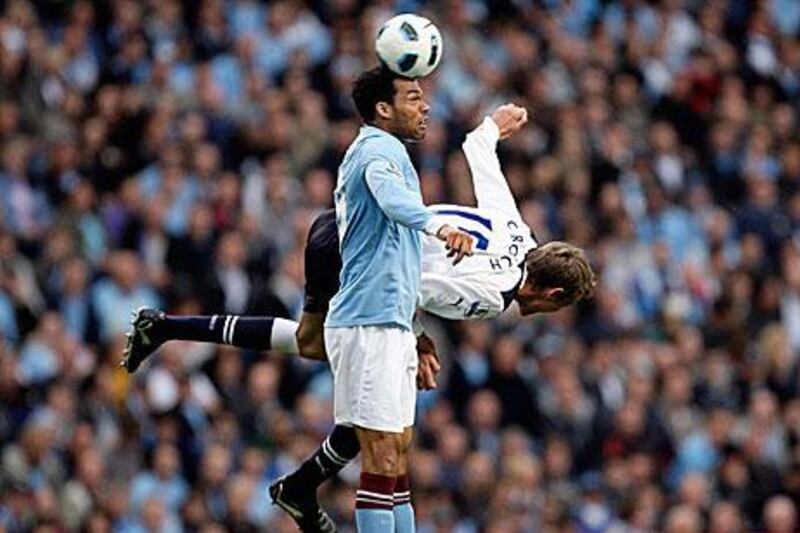Manchester City's Joleon Lescott wins the aerial battle from Peter Crouch.